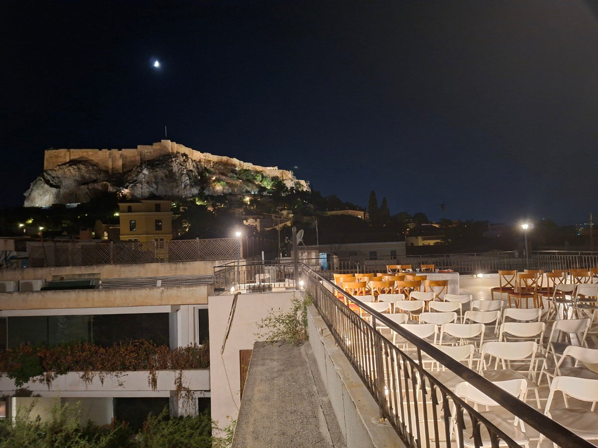 Athens at night with the illuminated Acropolis and a rooftop gathering space